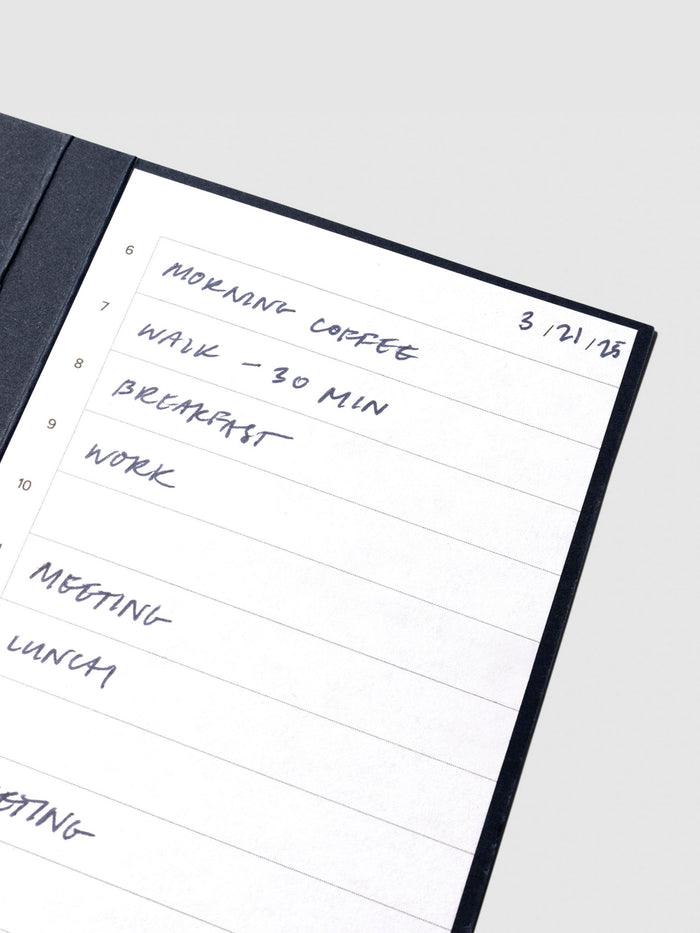 Closeup of sticky note displayed on its backing on a neutral background. A writing sample is filled out on the page.