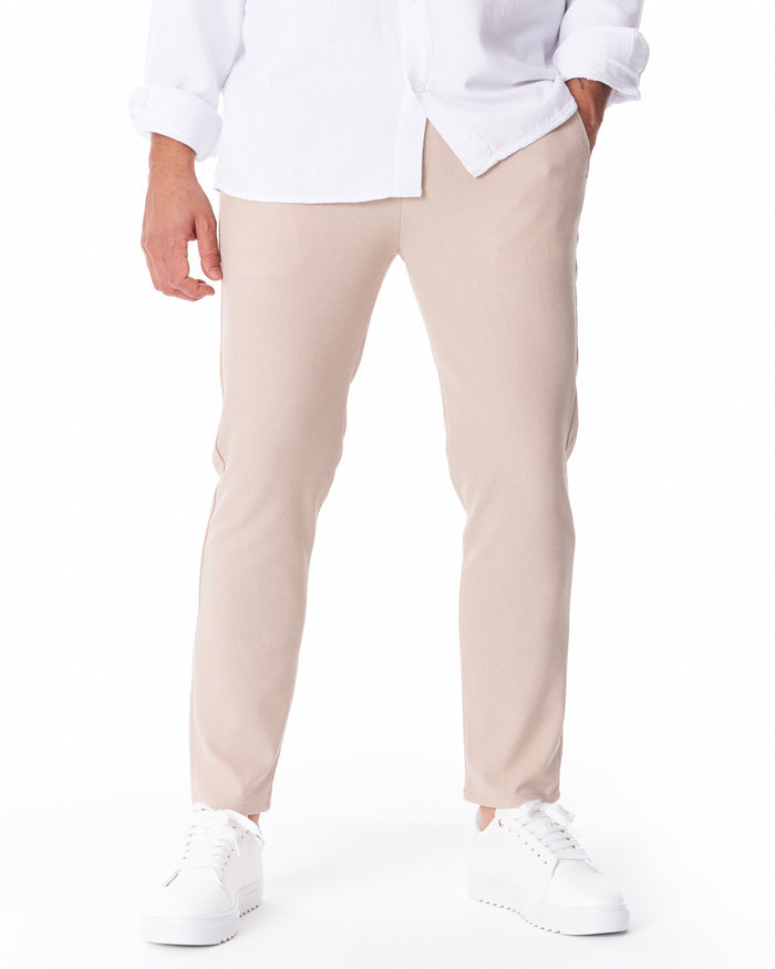 Martin Valen men's beige lightweight trousers, front view mid-shot with model standing, hand in pocket, ankle-length