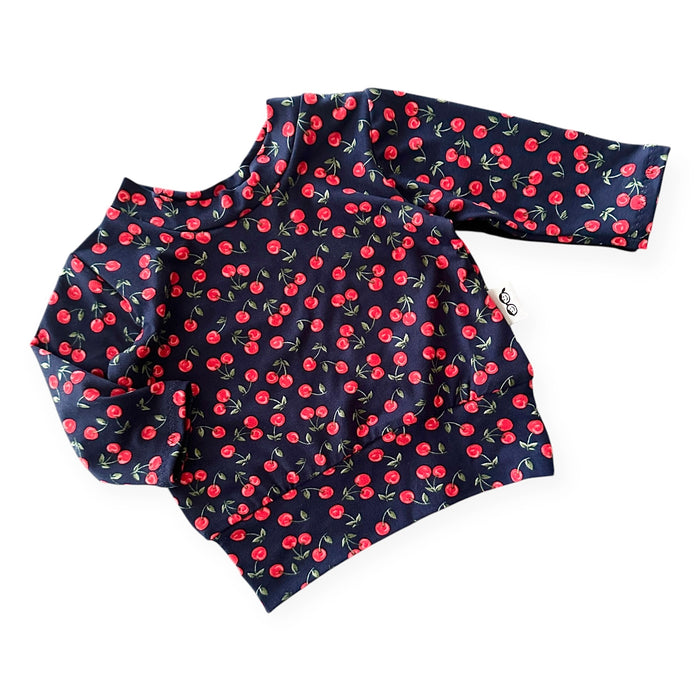 Midnight Cherries baby sweatshirt – soft stretch pullover with a relaxed fit, featuring a charming cherry print on a navy background. Handmade cozy toddler top for stylish comfort.