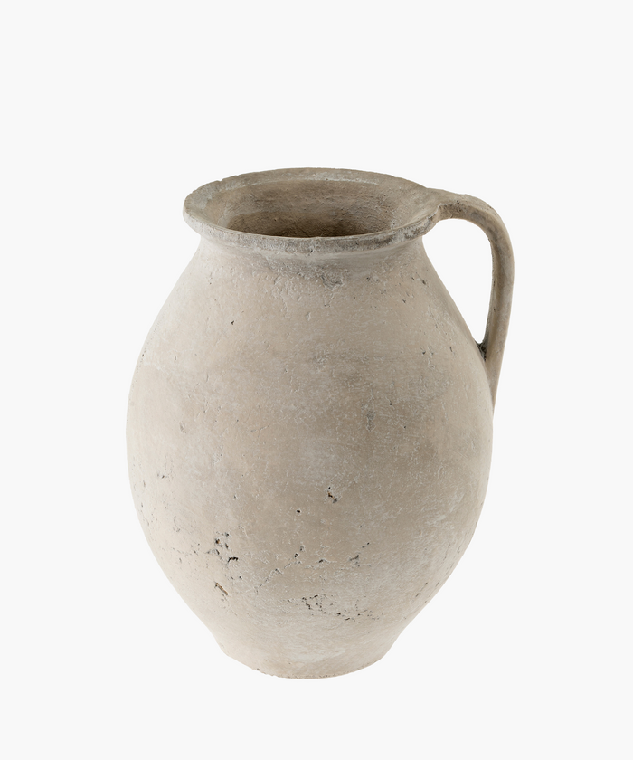 A weathered, ancient clay pot with a single handle is shown. Its surface is rough and textured, suggesting age and history. The tone is earthy and rustic. | Wildwood Home Co.