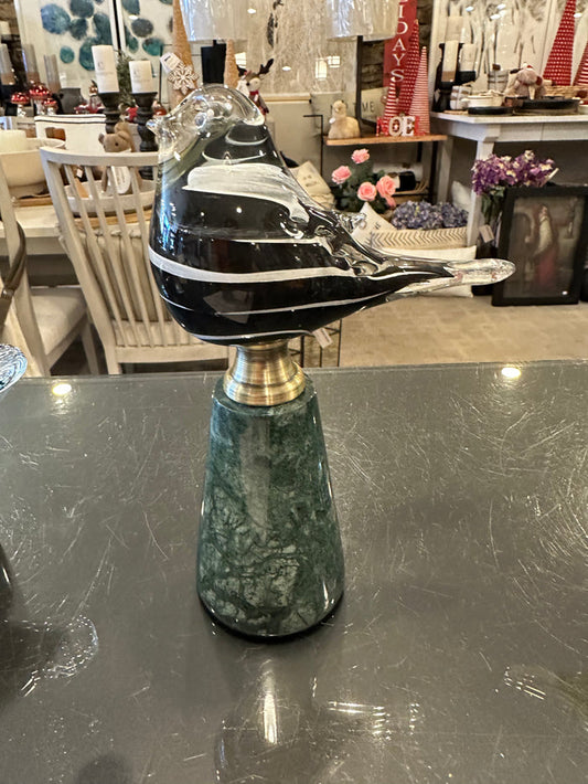 Glass black and white bird perched on a green marble pedestal with gold accent.