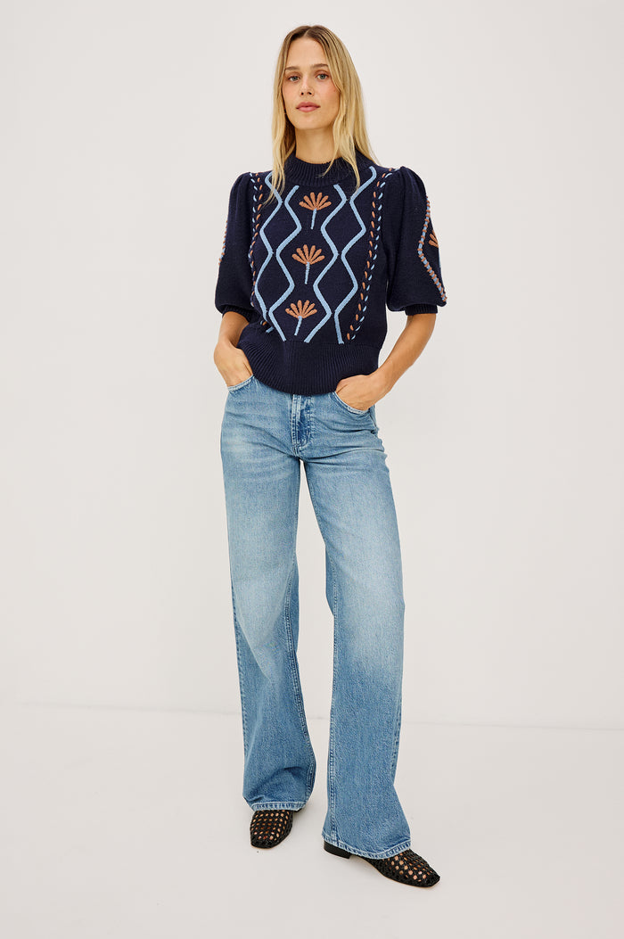 Addy Sweater in Cable Knit With Mock Neck, Relaxed Fit, and Elbow-Length Puff Sleeves in Floral Cables - Full Body Front View Featured on Model