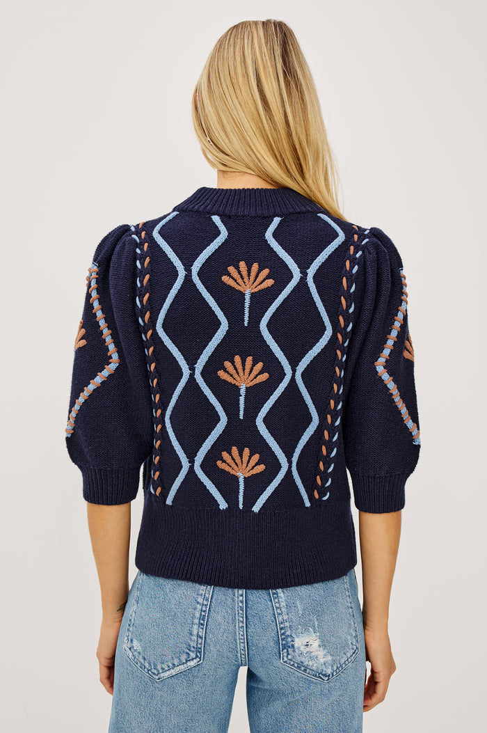 Addy Sweater in Cable Knit With Mock Neck, Relaxed Fit, and Elbow-Length Puff Sleeves in Floral Cables - Upper Body Back View Featured on Model