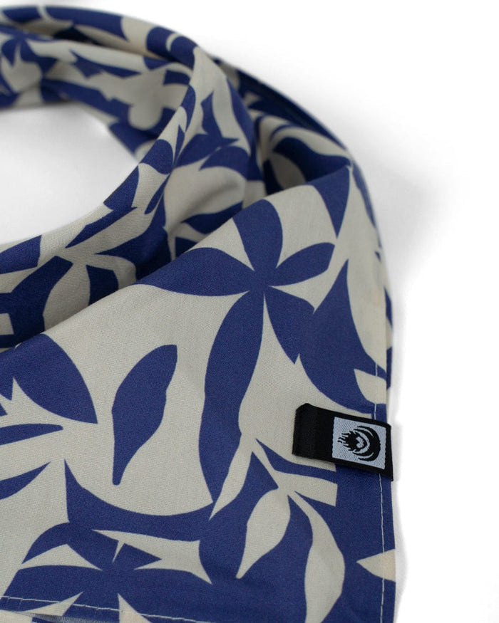 The Saltrock Balance Bandana in blue features an abstract leaf pattern, a small black and white eye tag in the corner, and is made from 100% cotton with a square cut.