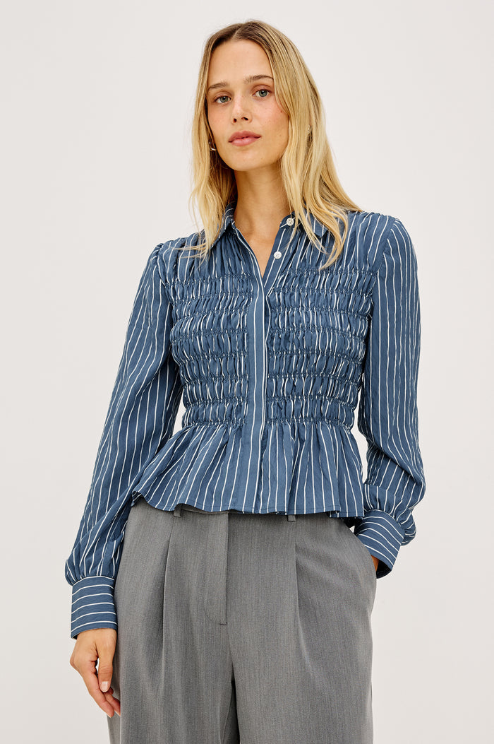 Bradshaw Shirt in Cotton Poplin With Button-Up Front, Collar, Smocked Body, Peplum Hem, and Bishop Sleeves in Washed Indigo Stripe Colorway - Upper Body Front View Featured on Model