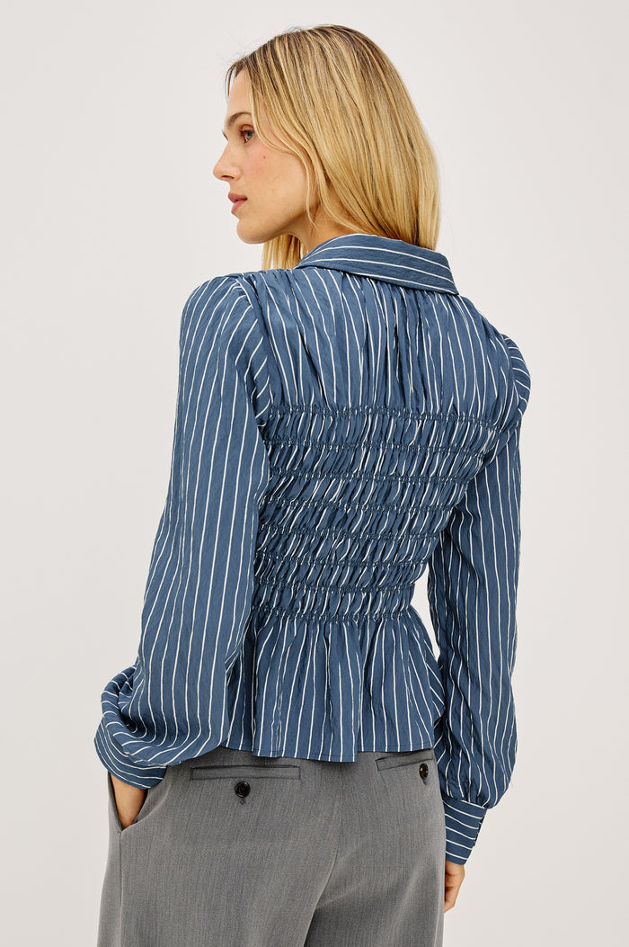 Bradshaw Shirt in Cotton Poplin With Button-Up Front, Collar, Smocked Body, Peplum Hem, and Bishop Sleeves in Washed Indigo Stripe Colorway - Upper Body Back View Featured on Model