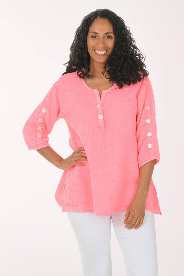 Woman wearing a pink blouse with white buttons on a white background