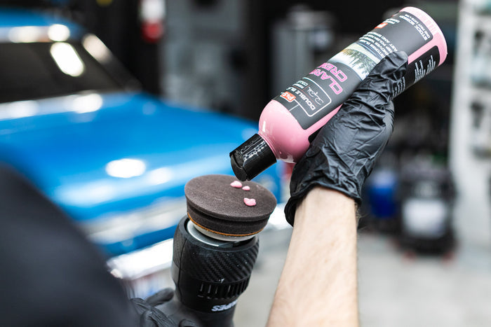 Person pouring P&S Clarity Creme onto a Rupes polisher with a blue car in the background