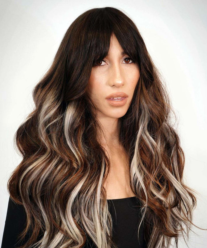 A woman with long, wavy dark brown hair and curtain bangs wears black Clip-In Bangs, paired with a black top on a light background.