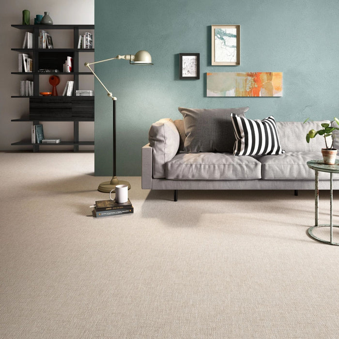 Living room featuring beige fabric effect floor tiles, a grey sofa, a black floor lamp and a teal wall with framed art.