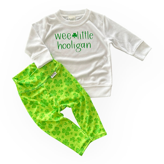 Adorable St. Patrick's Day outfit for babies and toddlers, featuring a 'Wee Little Hooligan' white pullover paired with bright green shamrock leggings. Perfect for festive celebrations or everyday wear.