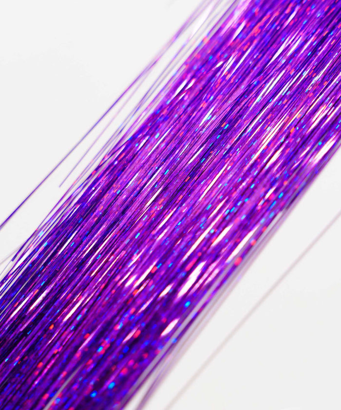 Close-up of Perfect Locks Perfect Hair Tinsel in shimmering Emerald, metallic strands diagonal on white, like vibrant hair extensions.#color_royal-purple