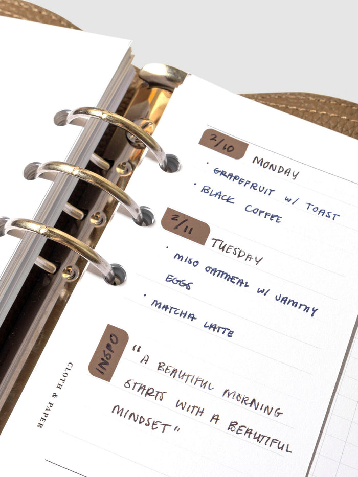 Insert in use inside a leather planner. It has sample text filled out and several stickers decorate different sections of the insert.