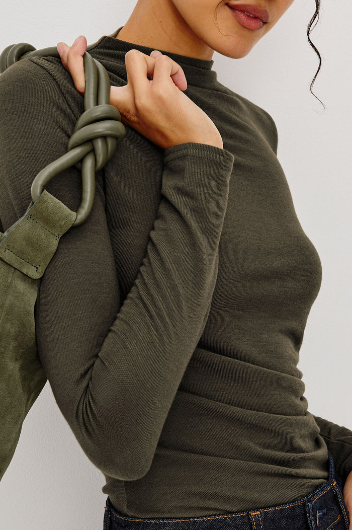 Joelle Top Fitted in Jersey With High Funnel Neckl, Long Sleeves, and Asymmetric Shoulder Shirring in Heather Olive Colorway - Upper Body Front Close Up View Featured on Model