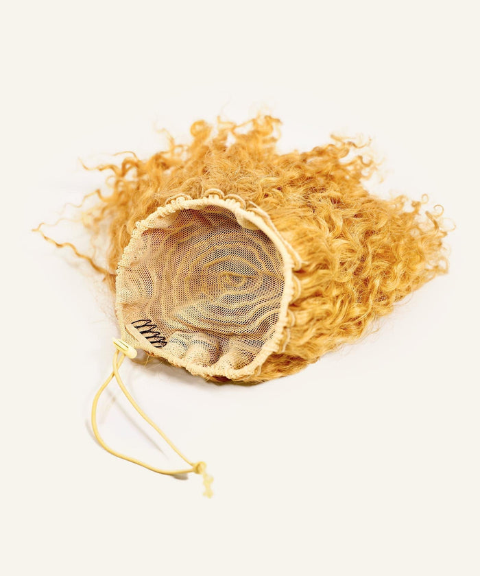 The Perfect Locks Kinky Curly Clip-In Bun in Golden Brown  is a human hairpiece with an elastic drawstring and mesh cap, shown on a neutral background.#color_honey-blonde-(27)