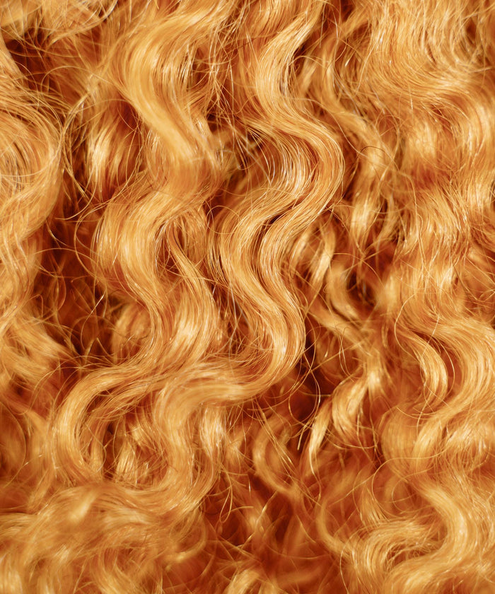 Close-up of the Perfect Locks Kinky Curly Clip-In Bun in Honey Blonde , with shiny, textured curls filling the entire frame.#color_honey-blonde-(27)