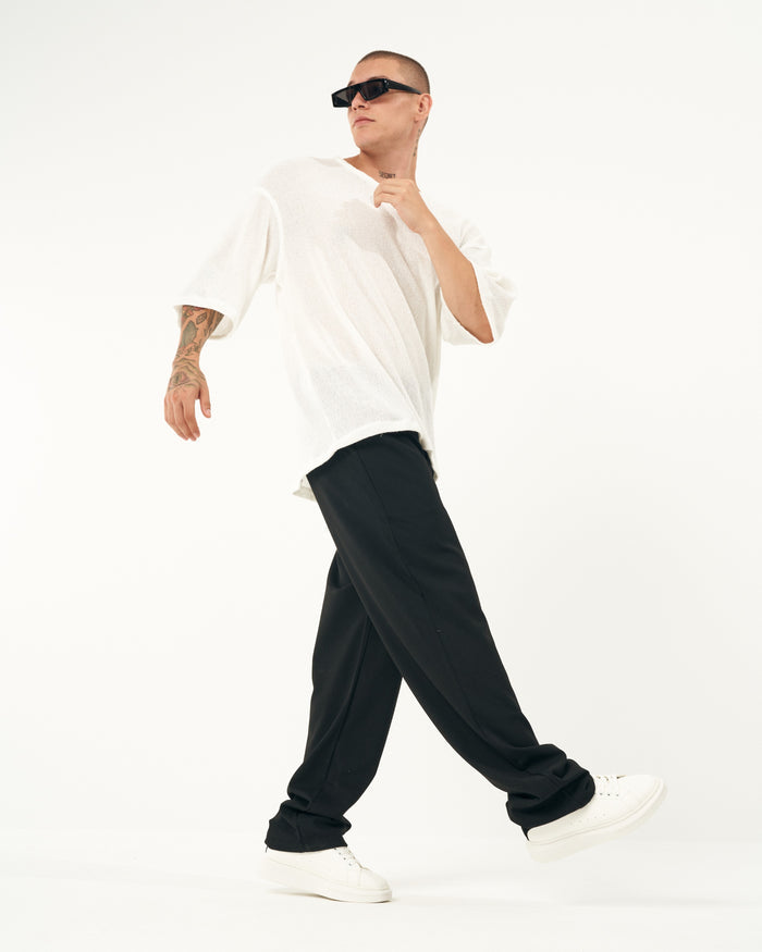 Martin Valen men's oversized loose-fit black sports pants, side walking view showing long relaxed hem