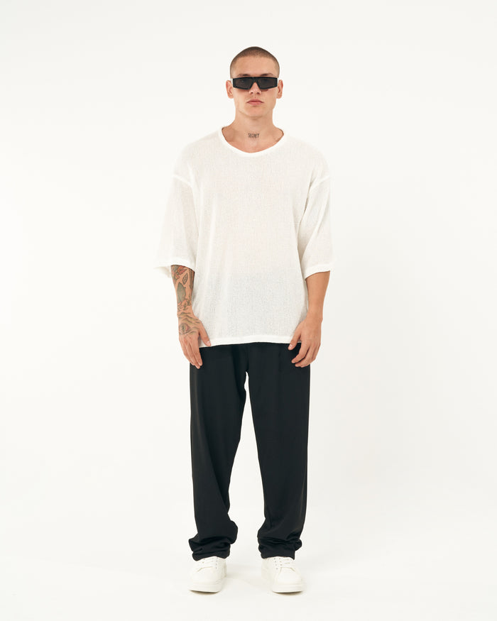 Martin Valen men's oversized black sports pants, three-quarter lower view showing straight legs and stacked hems over white sneakers