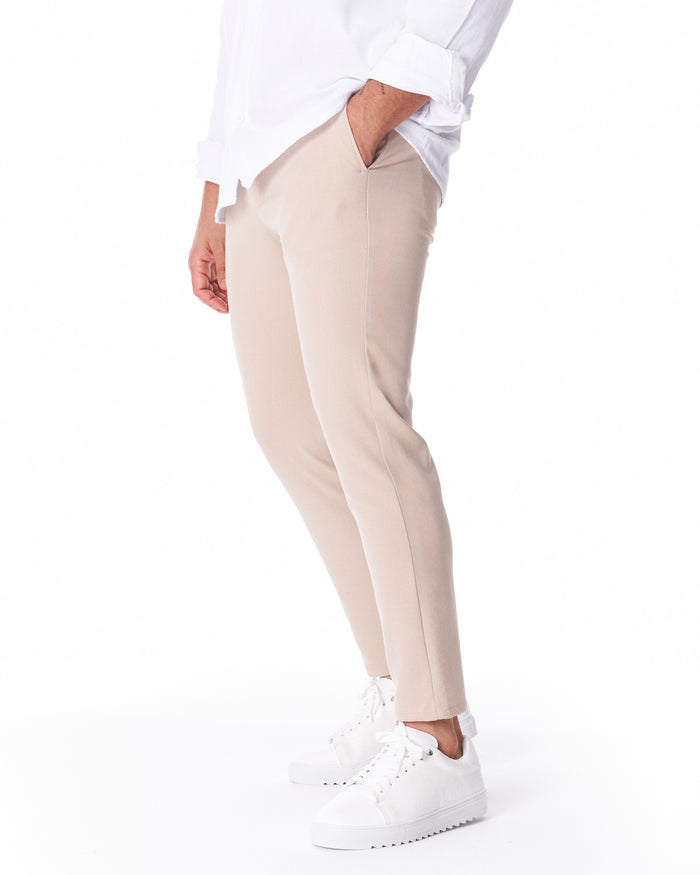 Martin Valen men's light beige trousers in lightweight fabric, three-quarter side view with hand in pocket and visible side pocket