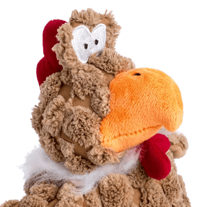 Close up of brown chicken dog toy with orange beak, red comb and wattle sat on a white back ground.