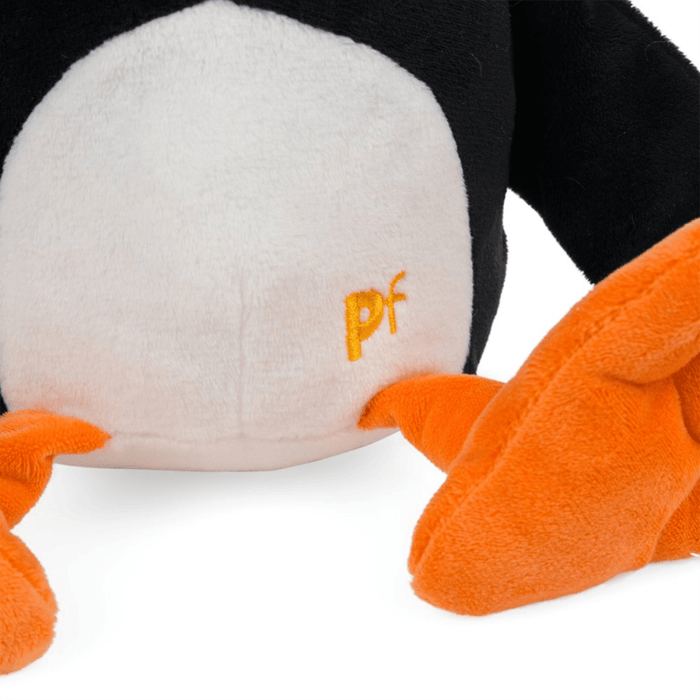 Close up of Plush Puffin dog toy with orange feet, stitching detail of text 'PF' sat on white background.