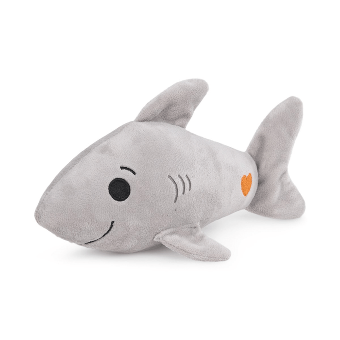Side view of grey plush toy shark with orange heart detail on tail on white background.