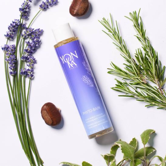 Bottle of Phyto Bain - Invigorating, Relaxing Aromatic Bath I Yon-Ka Paris surrounded by fresh lavender, rosemary, and nut ingredients, highlighting natural skincare and body care wellness.