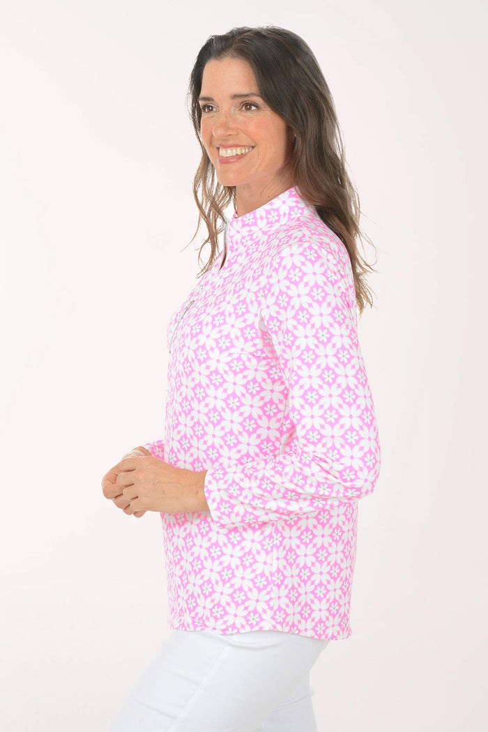 A woman wearing a long sleeve pink and white flower activewear top.