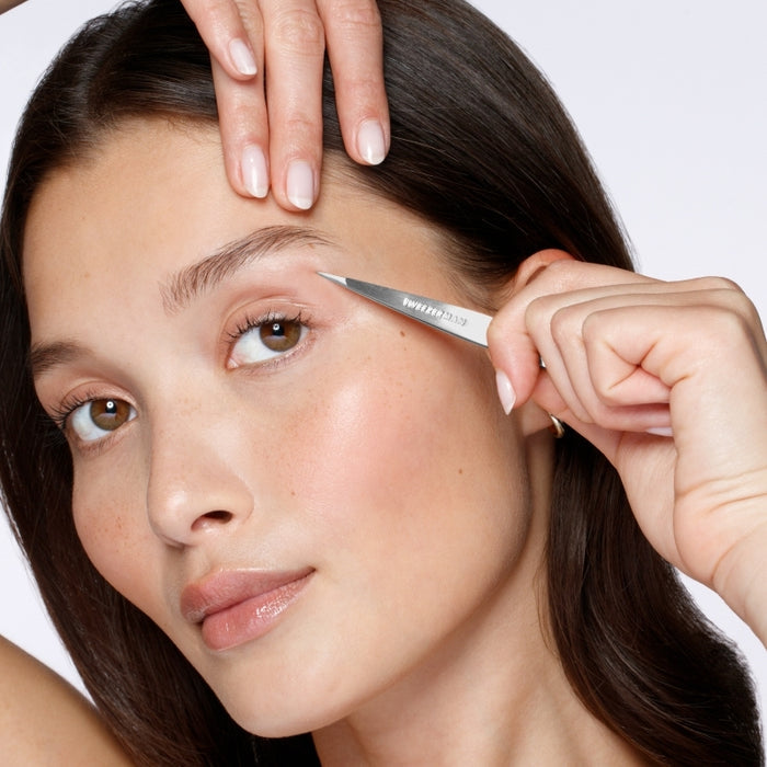 Woman using Point Classic Tweezer | Tweezerman to shape her eyebrow, demonstrating precise grooming for skincare and beauty care.