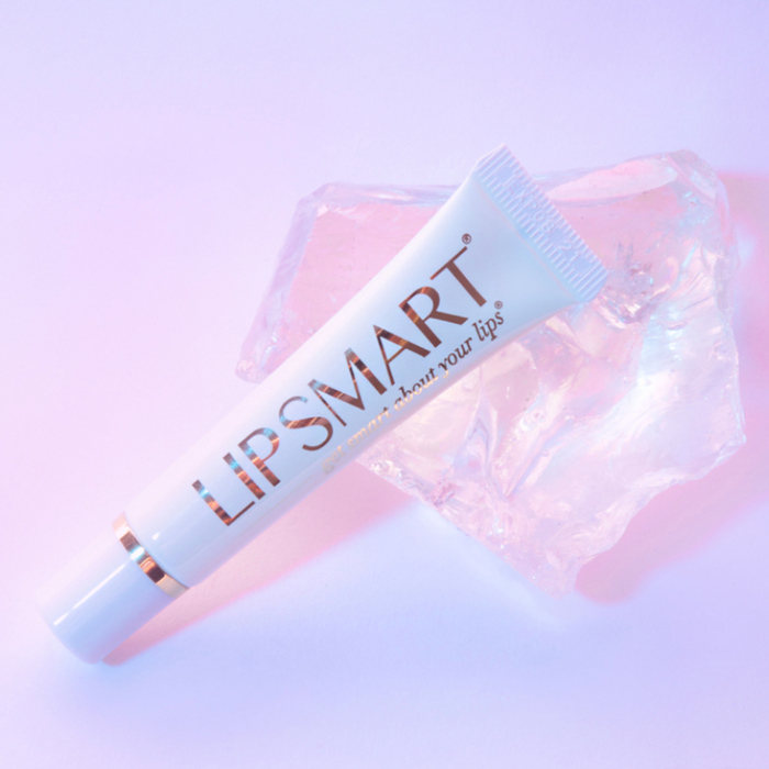 PREMIUM LIP BALM | LipSmart tube placed on a clear ice-like surface with soft pink and purple lighting, highlighting skincare and lip care wellness.