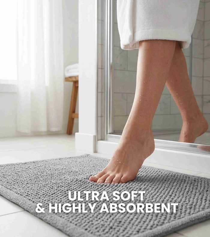 Grey bath mat on bathroom floor under bare foot, rectangular woven texture