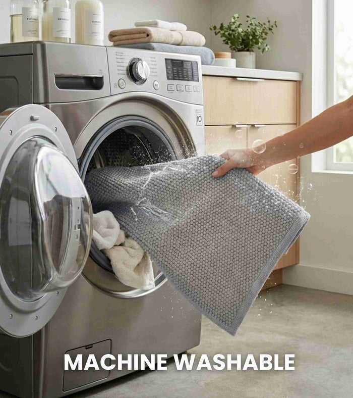 Grey bath mat being lifted over a washing machine, woven rectangular mat