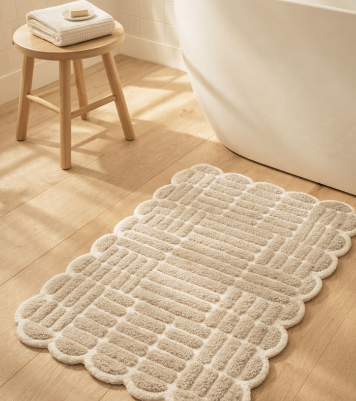 Beige woven bath mat with scalloped edges and anti-skid textured backing.