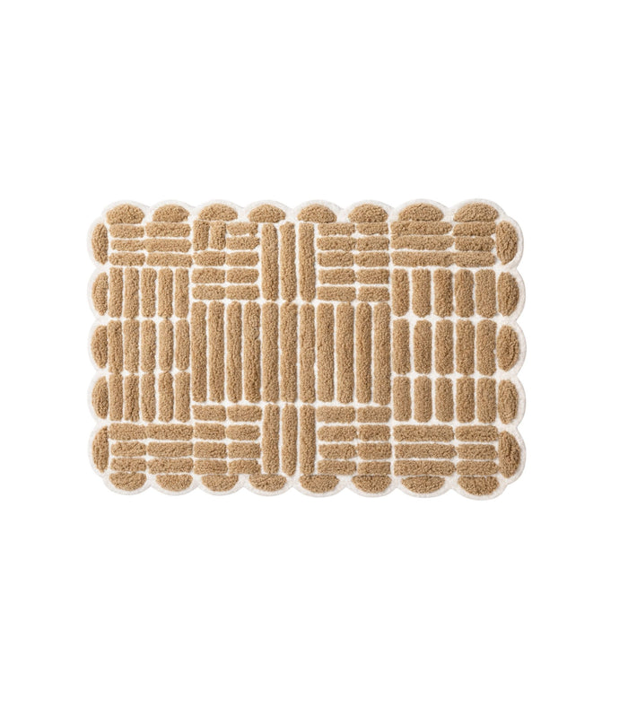 Beige bath mat with grid-loop pattern and scalloped edges, non-slip textured backing.