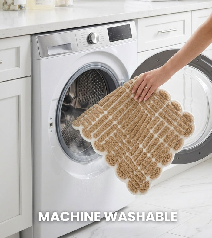 Tan bath mat folded near a washing machine opening, looped grid design with border.