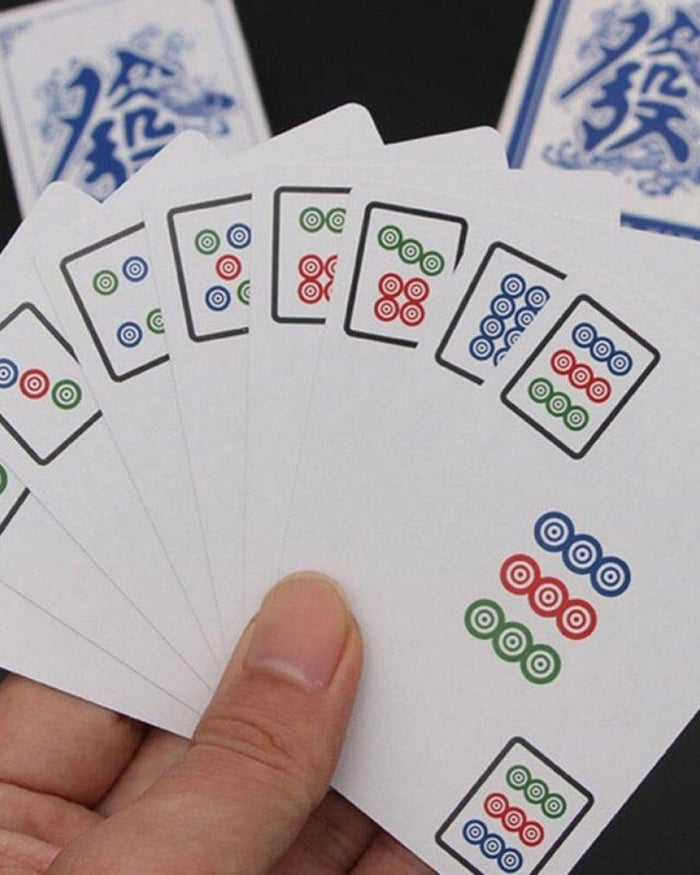 Mahjong playing cards with multicolor dot designs, held in a hand