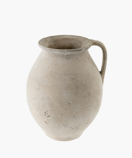 A weathered, ancient clay pot with a single handle is shown. Its surface is rough and textured, suggesting age and history. The tone is earthy and rustic. | Wildwood Home Co.