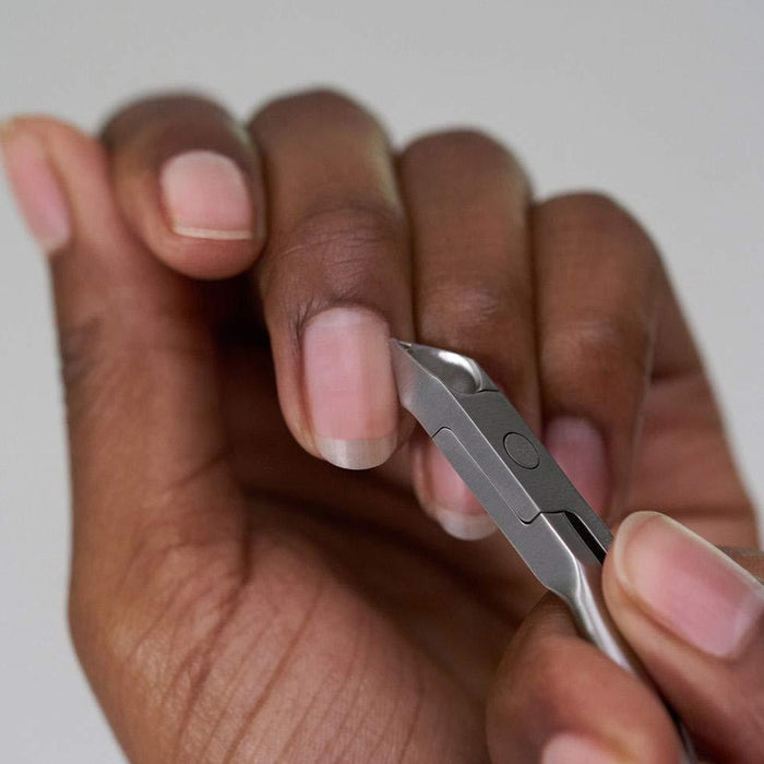 Close-up of a person using the Rockhard Cuticle Nipper | Tweezerman to carefully trim their cuticles for precise skincare and nail care grooming.