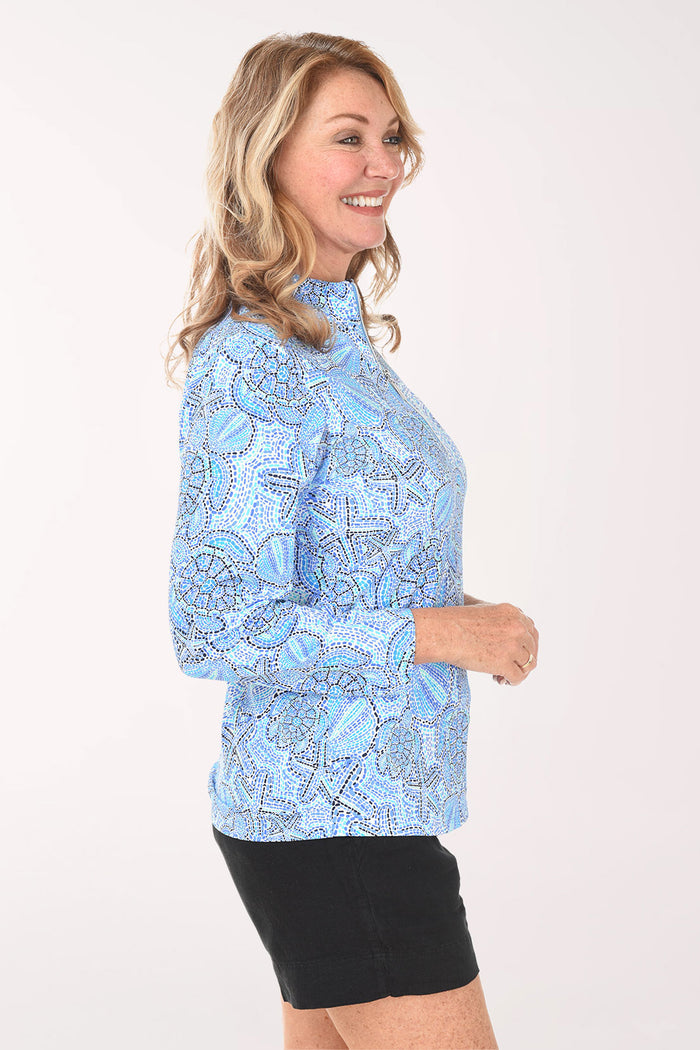 Woman wearing a blue patterned long-sleeve shirt and black shorts on a white background