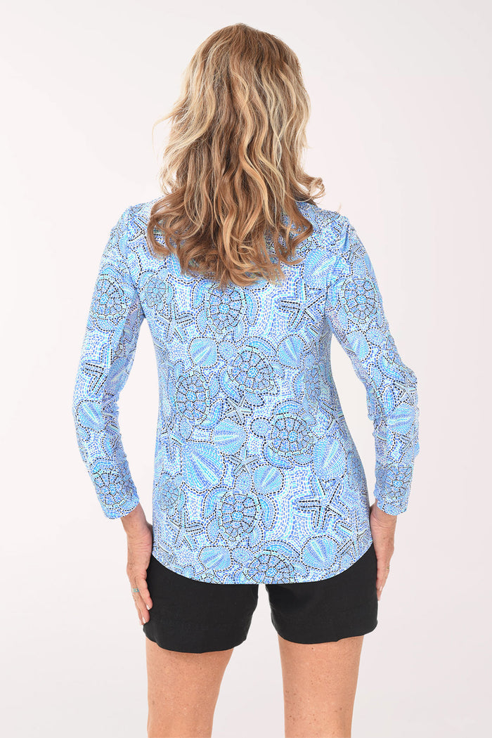 Woman wearing a blue patterned long-sleeve shirt and black shorts on a white background