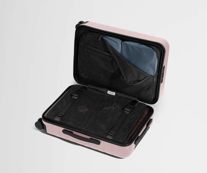 Pink suitcase with open compartment on a light gray background
//
Our signature interior compression system allows you to stay more organized. Paired with The Insider Packing Cubes.