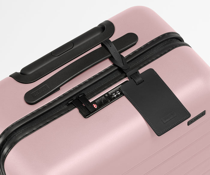 The Bigger Carry-On suitcase in Blush Pink shown shown from above highlighting TSA-approved combination lock and recycled leather luggage tag
//
All of our suitcases come with a leather luggage tag. Add up to three letters to personalize yours and stand out at the baggage claim.