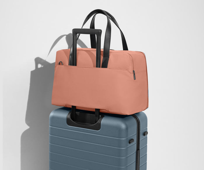 The Overnight Bag secured to an Away checked suitcase using the trolley sleeve
// Our duffles are designed with a trolley sleeve that slides onto your suitcase to keep it in place while you’re on the move. Paired with The Medium.