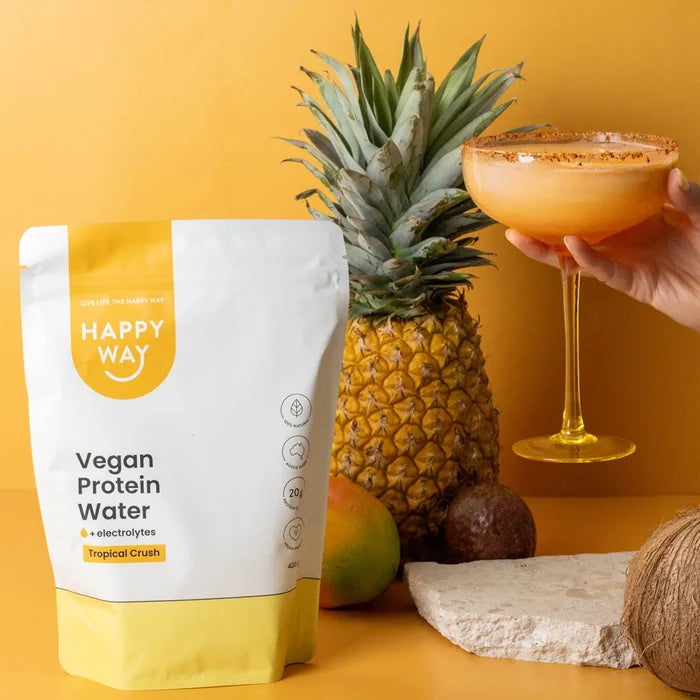 Happy Way Vegan Protein Water package with a cocktail, pineapple, and mango on a yellow background