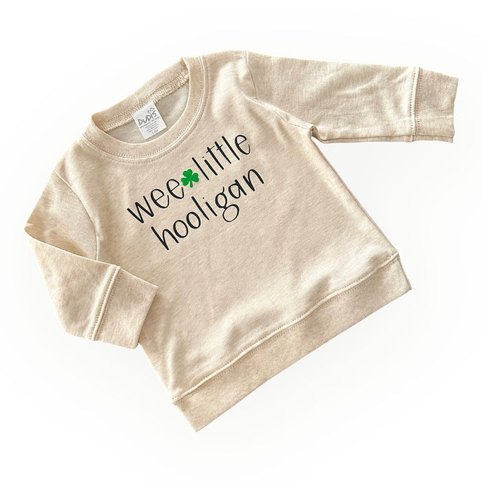 Adorable 'Wee Little Hooligan' cream pullover for babies and toddlers, featuring a playful St. Patrick's Day shamrock design. Soft, cozy, and perfect for festive celebrations or everyday wear. Made for comfort and style!